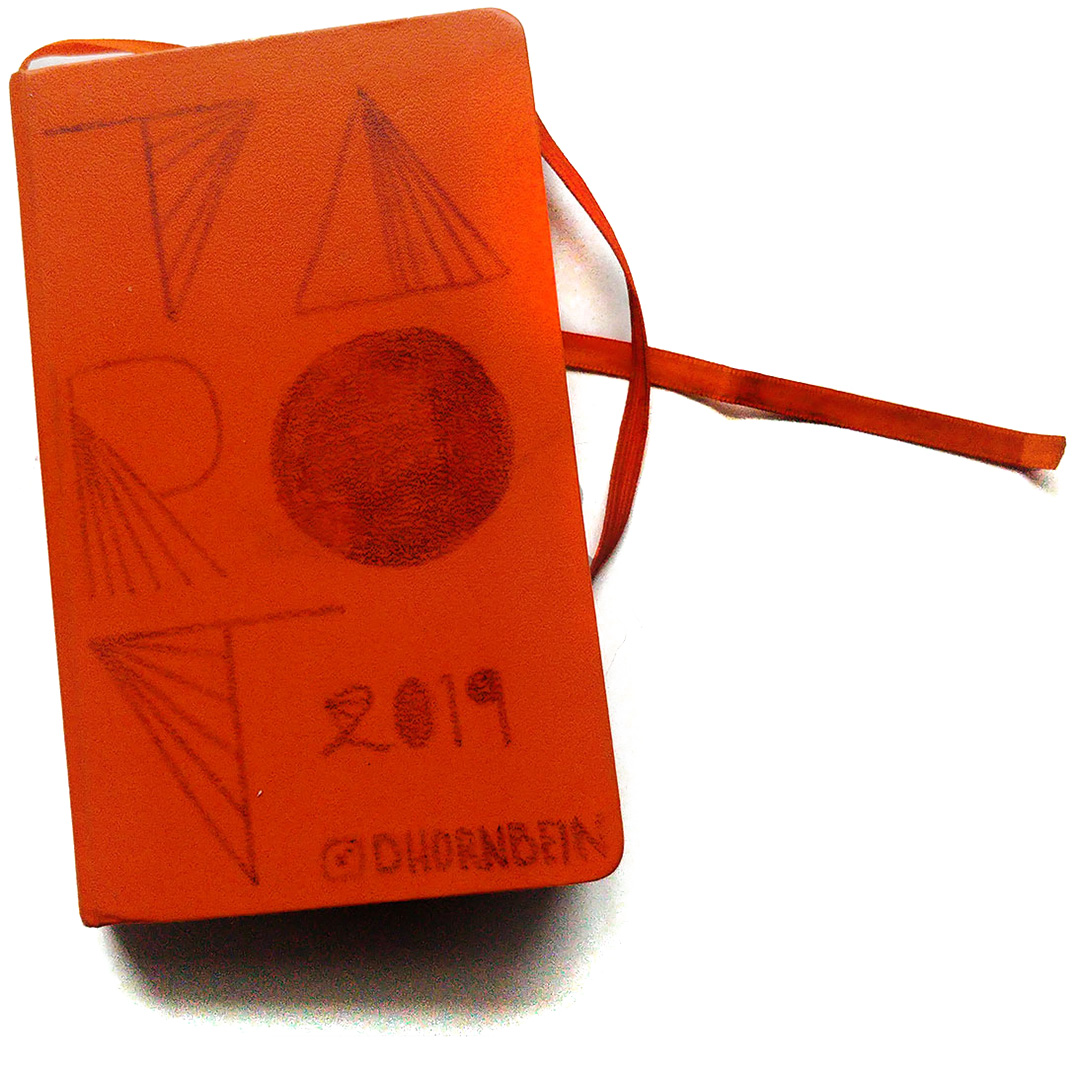 A bright orange sketchbook with the words TAROT on the cover